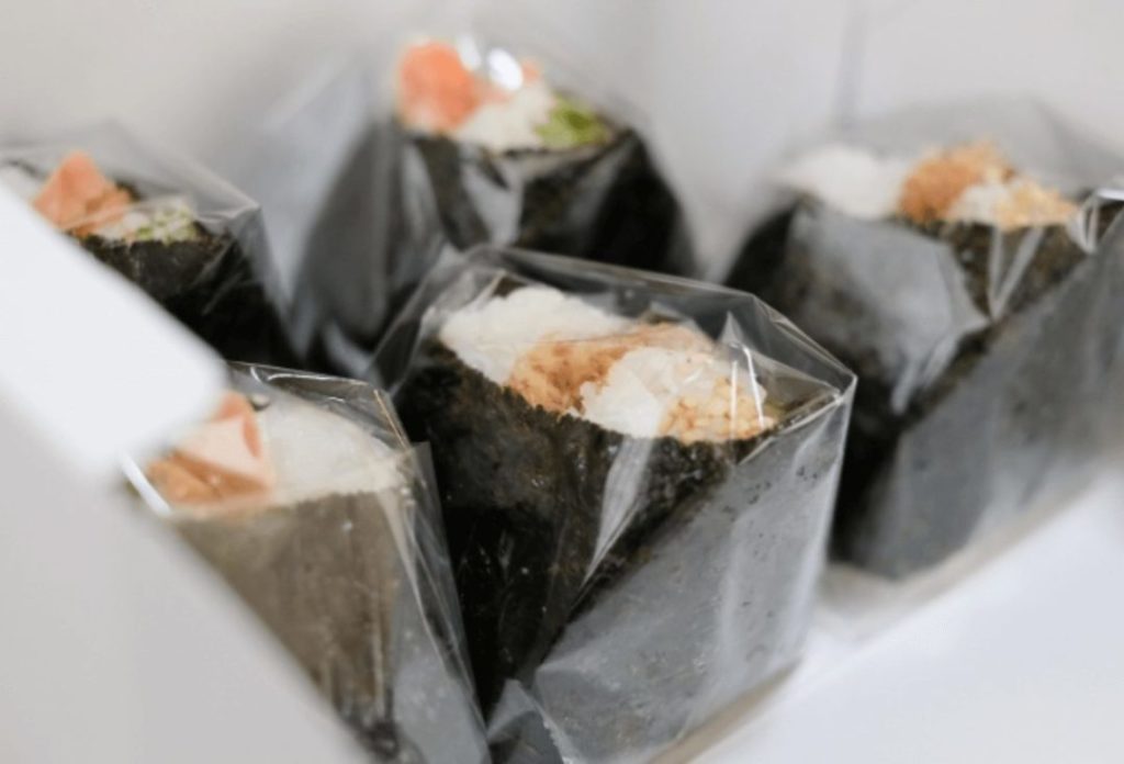 Various types of rice balls lined up on the shelves of a convenience store