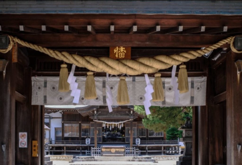 Large shimenawa rope decorated on the gate of a shrine made of straw